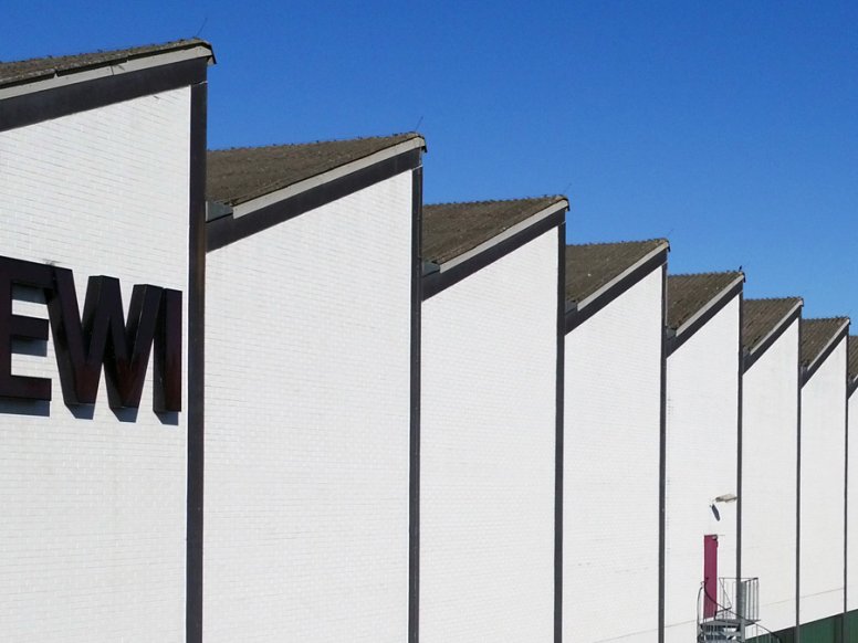 HEWI factory with white façade, "HEWI" lettering and shed roof